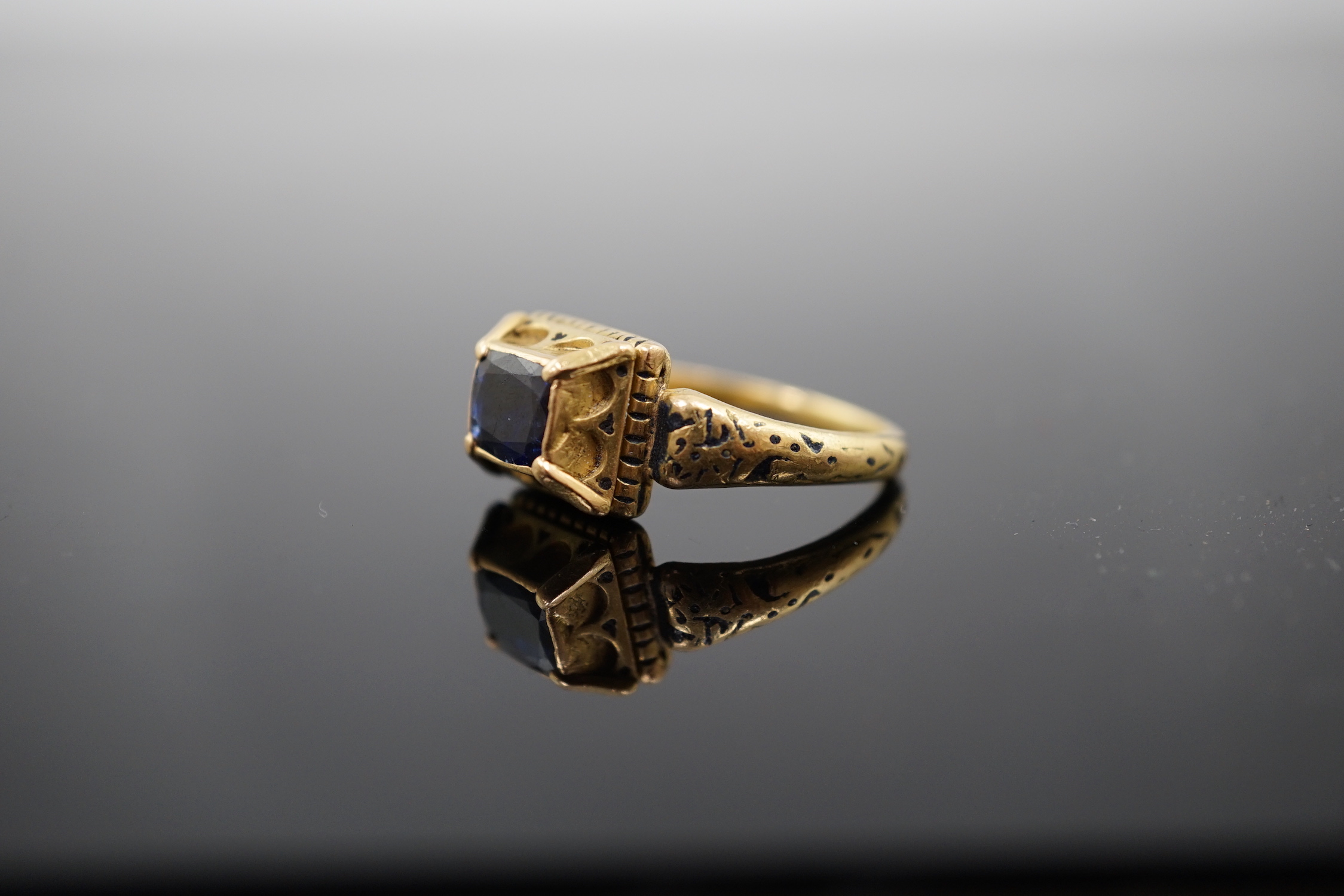An antique high carat gold, black enamel and collet set cushion cut sapphire set 'poison' ring